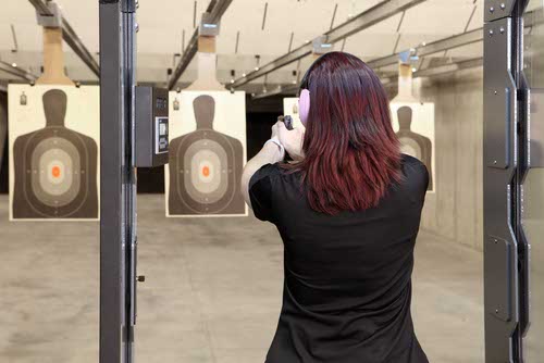 Woman aiming pistol at indoor shooting range