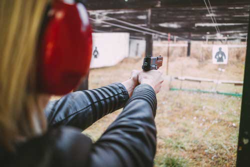 Woman aiming pistol at outdoor shooting range